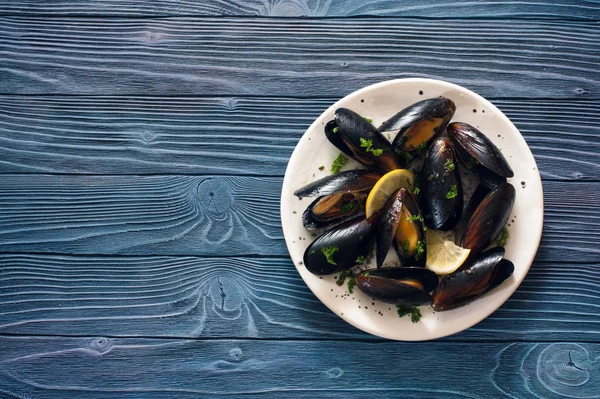 Cozze su piatto bianco su sfondo di legno blu — Foto Stock