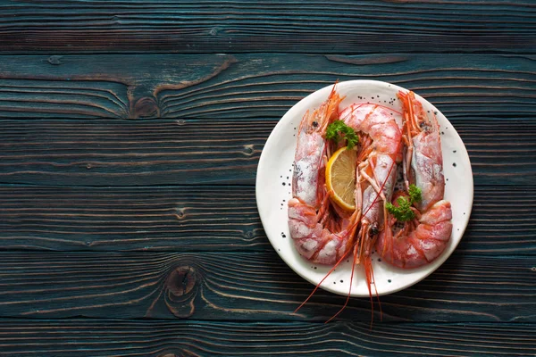 Large shrimps on white plate over wood dark background — Stock Photo, Image