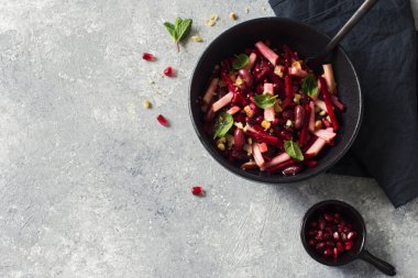 Gri bir arka planda siyah tabakta pancar, elma ve kırmızı fasulye vegan salatası yakın plan. Düz yatıyordu. Boşluğu kopyala