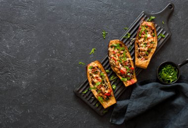 Et, mantar ve domatesle doldurulmuş patlıcanlar taştan bir arka planda siyah bir seramik tabakta servis ediliyor. Düz yatıyordu. Boşluğu kopyala