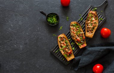 Et, mantar ve domatesle doldurulmuş patlıcanlar taştan bir arka planda siyah bir seramik tabakta servis ediliyor. Düz yatıyordu. Boşluğu kopyala