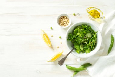 Beyaz ahşap arka planda taze sebze salatası, kombine, bezelye ve çam fıstığı. Düz yatıyordu. Boşluğu kopyala