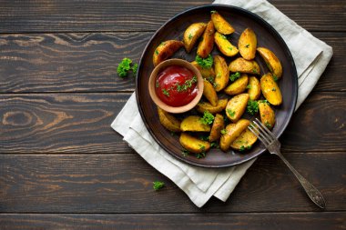 Kızarmış patates ve bir kase domates sosu. Ahşap bir zeminde, koyu kil bir tabakta. Düz yatıyordu. Boşluğu kopyala