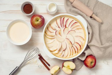 Beyaz ahşap arka planda ev yapımı elmalı turta ve pişirme malzemeleri. Düz yatıyordu