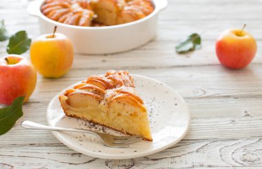 Beyaz ahşap arka planda ev yapımı elmalı turta ve taze elmalar yakın plan.