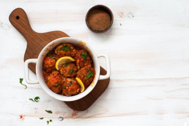 Domates soslu köfteler beyaz ahşap arka planda kapanıyor. Düz yatıyordu