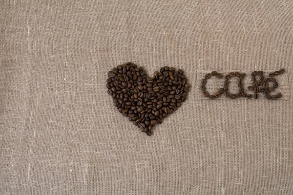 Grains de café torréfiés, lin, le mot café en français, café, carte, en espagnol, coeur , — Photo