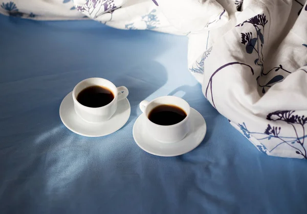 Két fehér csésze kávé van az ágyban, napfényes reggel — Stock Fotó
