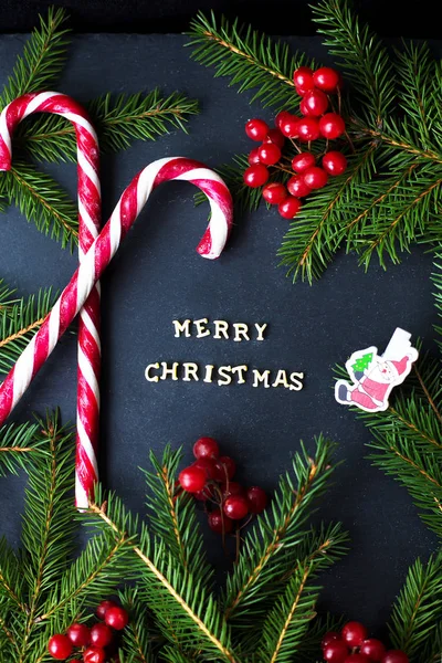 Snoep op zwarte achtergrond met takken van bomen. De inscriptie Merry Christmas — Stockfoto