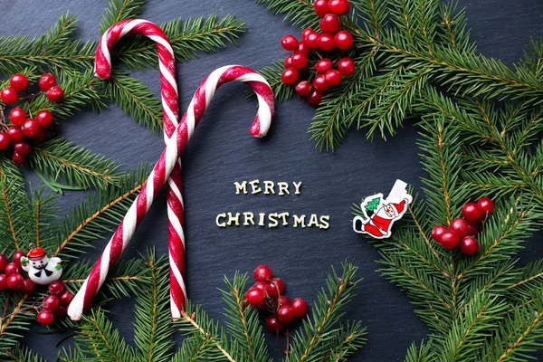 Caramelle su sfondo nero con rami di alberi. L'iscrizione Buon Natale — Foto Stock