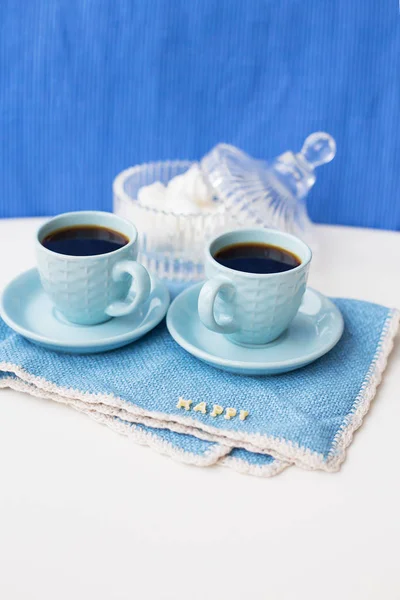Two blue coffee cups on blue napkin with the words happy