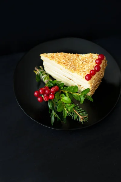 Piece of cake decorated Christmas tree and red berries on a black background — Stock Photo, Image