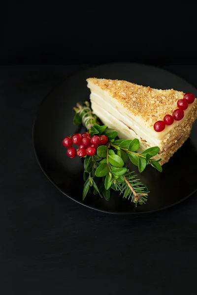 piece of cake decorated Christmas tree and red berries on a black plate