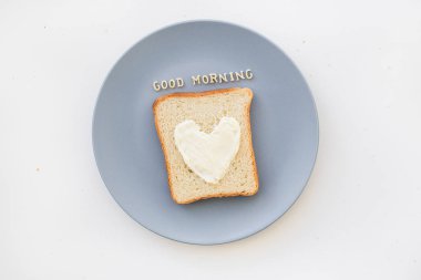 Kahvaltı için kalp şeklinde sandviç ve mavi tabakta peynir. Günaydın.
