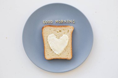 Kahvaltı için kalp şeklinde sandviç ve mavi tabakta peynir. Günaydın.