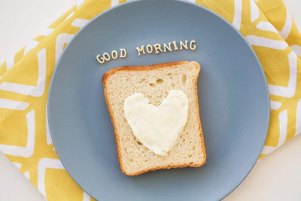 Kahvaltı için kalp şeklinde bir sandviç tabakta küflü peynir ve peçeteli parlak bir yazı. Günaydın.