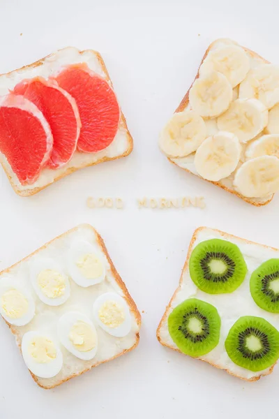 Bright mix of sandwiches for breakfast (fruit, vegetables, fish, eggs) inscription good morning — Stock Photo, Image