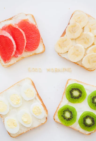 Bright mix of sandwiches for breakfast (fruit, vegetables, fish, eggs) inscription good morning — Stock Photo, Image