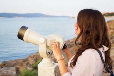 Kız teleskopla denize bakıyor..