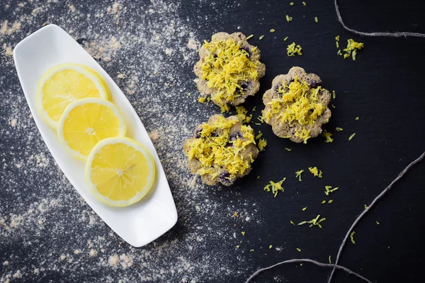 Lemon cupcakes on a black background and a lemon on a plate — Stock Photo, Image