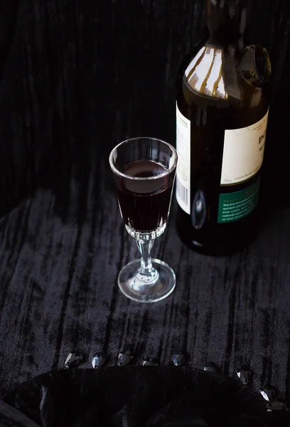 Botella y una copa de vino tinto sobre un fondo negro . — Foto de Stock