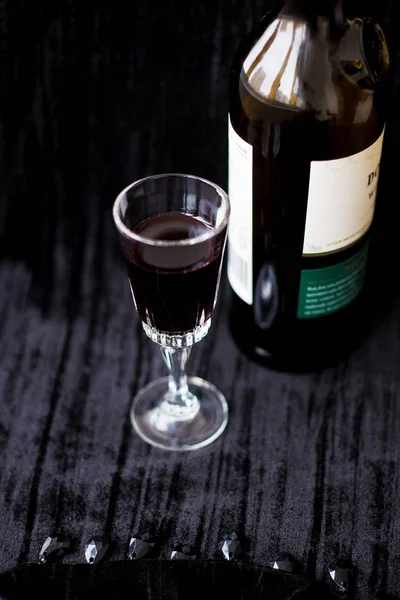 Botella y una copa de vino tinto sobre un fondo negro . — Foto de Stock