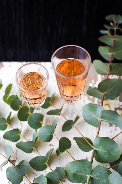Ramas de eucalipto sobre una mesa vieja con una copa de vino de rosas . — Foto de Stock