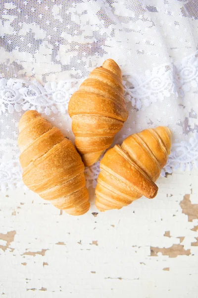 Beautiful and delicious croissants on the background of old laces and white table — Stock Photo, Image