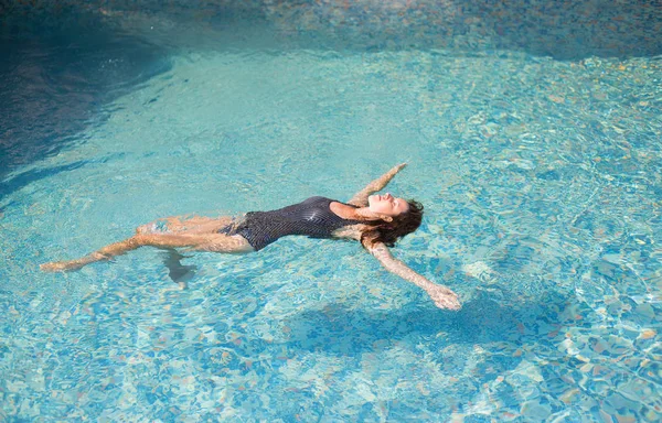 Güzel kız havuzda sırtüstü yüzme