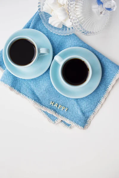 Two blue coffee cups on blue napkin with the words happy