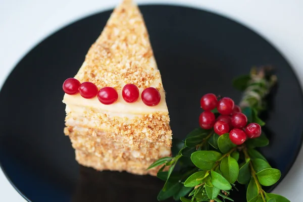 piece of cake decorated with branches of trees and berries viburnum on a black plate