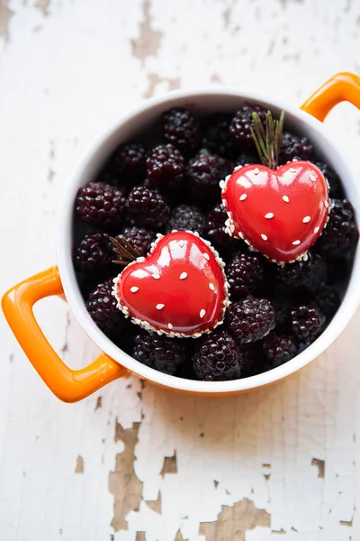 A full blackboy plate with a dessert in the form of a heart stands on a wooden background, close-up