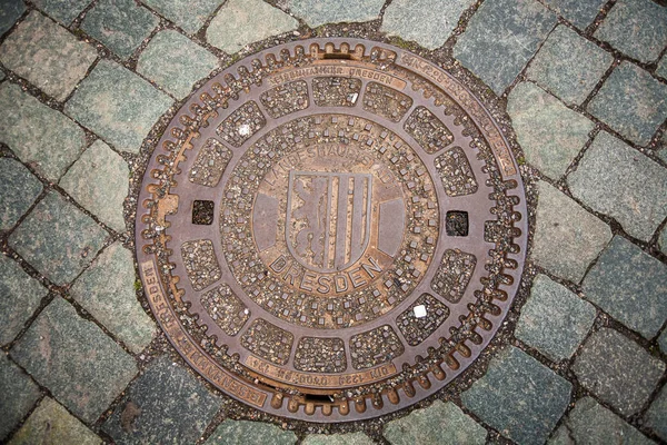 Portello rotondo in ferro per fogna su pavimentazione in ciottoli. Dresda, Germania. Pozzetto in acciaio nel marciapiede — Foto Stock