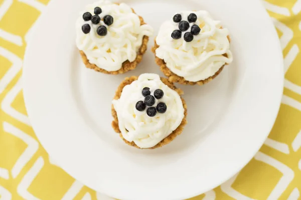 Hausgemachte Muffins mit Blaubeeren, Sahne und frischen Beeren auf gelber Serviette — Stockfoto