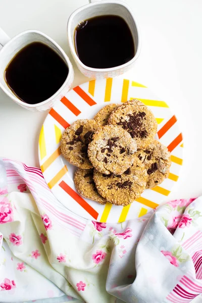 Galletas de avena con chocolate en un plato con paño brillante y dos tazas de café — Foto de Stock