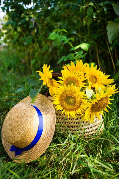 帽子、ひまわりの花束は緑の芝生の上のわら袋にあります. — ストック写真