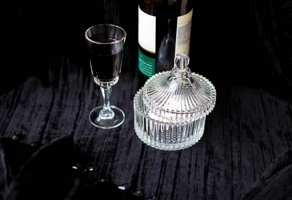 Dulces, botella y una copa de vino tinto sobre fondo negro — Foto de Stock