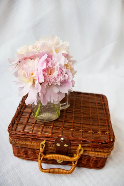 Дуже красивий букет з рожевих півоній у вазі стоїть на дерев'яній валізі . — стокове фото
