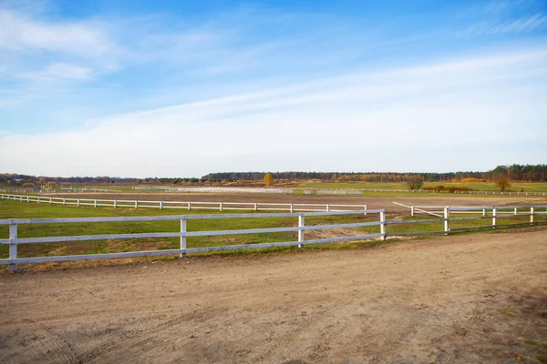 Trävitt staket på ett grönt fält. Vacker blå himmel. — Stockfoto