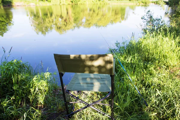 Poltrona per la pesca sul lago. Canna da pesca in acqua — Foto Stock