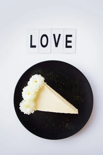 Creamy cheesecake, decorated with white flowers, close-up-inscription love — Stock Photo, Image