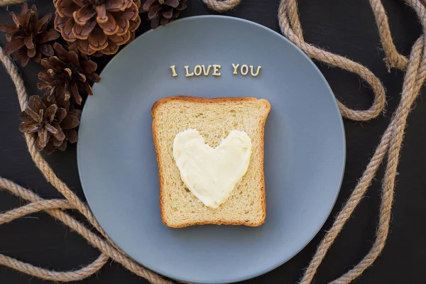 ブループレートにチーズ入りのハート型の朝食用サンドイッチとコーン碑文付きの黒い背景私はあなたを愛しています — ストック写真