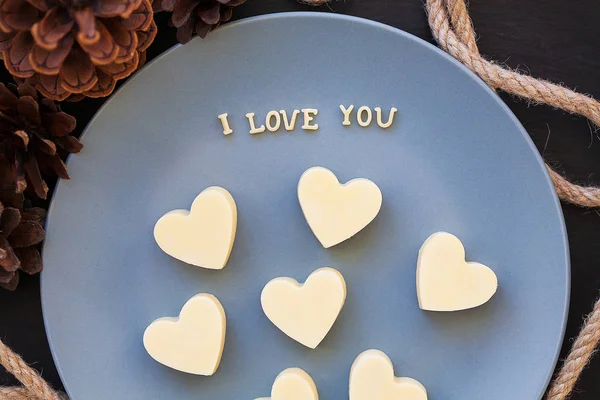 Candy white chocolate in heart, I love writing on a blue plate with cones — Stock Photo, Image