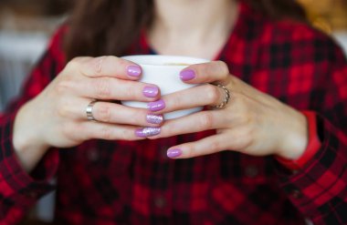 Kız elinde bir fincan kahve tutuyor. Yakın plan..