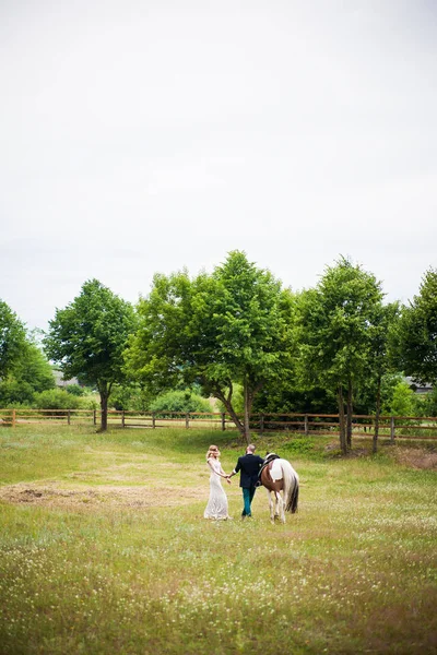 Hermosa novia y el novio están caminando con un caballo, estilo rústico —  Fotos de Stock