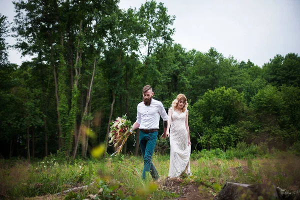 Hermosa novia y novio hipster pie en el fondo del bosque, estilo rústico —  Fotos de Stock