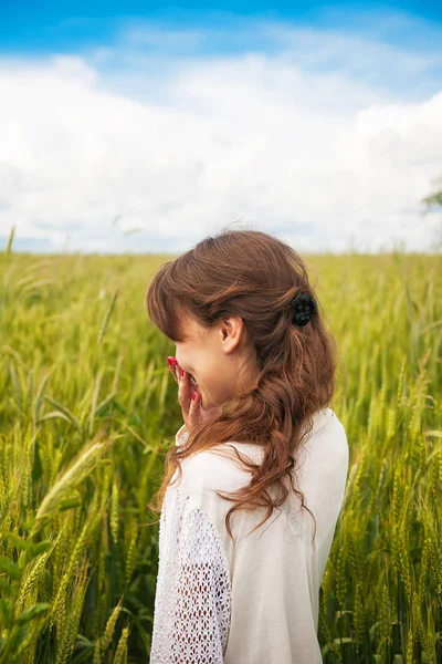 Schöne Mädchen in einem weißen Kleid steht in einem Weizenfeld — Stockfoto