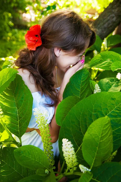 Young beautiful girl stands and laughs in big green leaves — Stock Photo, Image