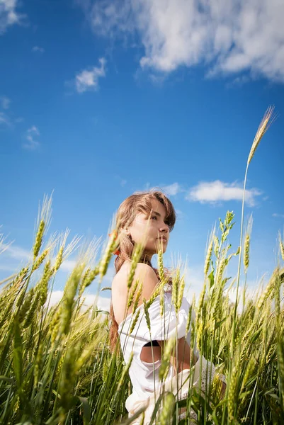 Schönes Mädchen steht in einem grünen Weizenfeld — Stockfoto