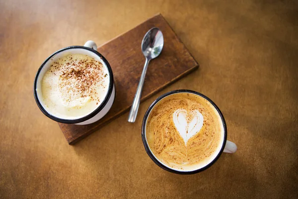 Két csésze cappuccino és latte állni egy fából készült asztal — Stock Fotó